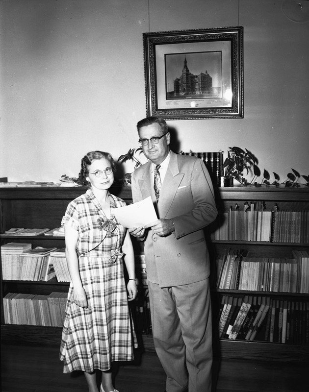 A portrait of President J.E. Buchanan standing in front of a bookshelf with an unidentified woman.
