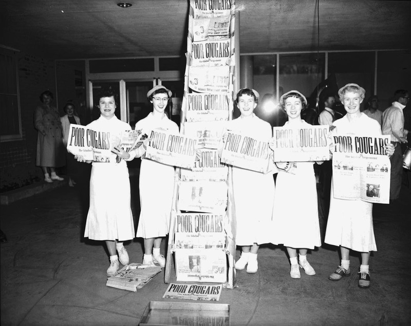 Students pose with newspapers that read "Poor Cougars" to celebrate that Idaho defeated WSC 10-0.