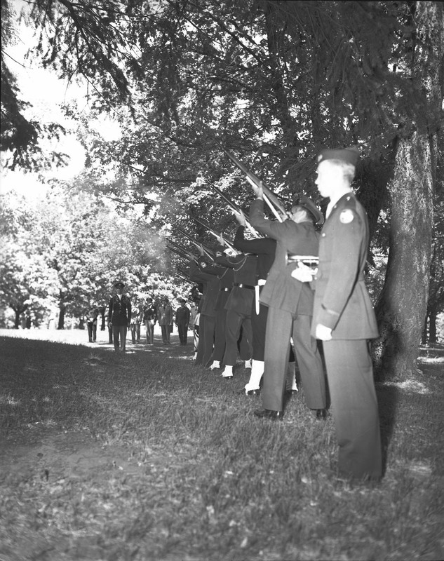 ROTC members in line with their rifles in the air.