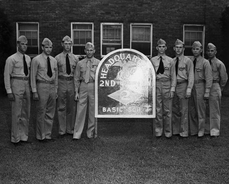 ROTC members posing beside the sign of their headquarters.