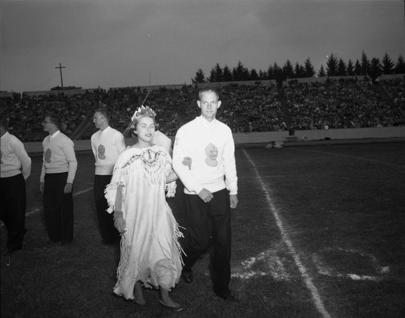 Costumed student being escorted off stage during the homecoming game.