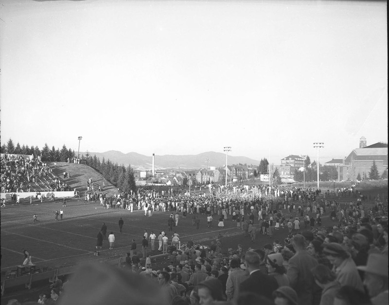 A crowd gathers on the football field at the Homecoming game.