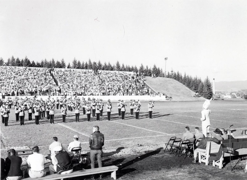 The University marching band playing on the field of the Homecoming game.