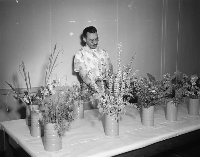 Harold McIlvaine examining vases of flowers.