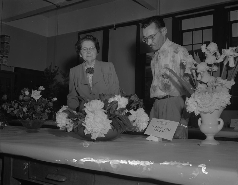 Harold McIlvaine and Mrs. Nelson examining floral arrangements.