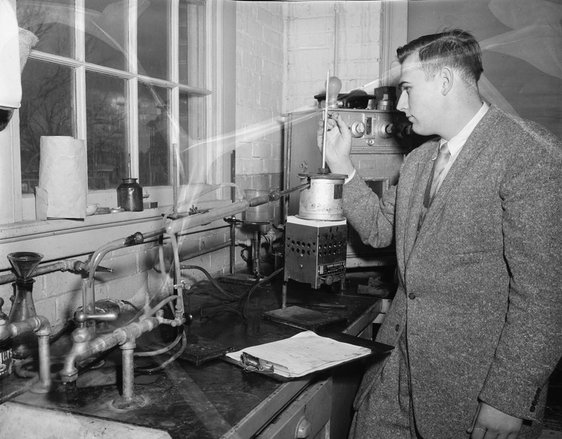 Francis E. Keller, Boise Petroleum scholar, checking distillation flask in College of Engineering asphalt laboratory.