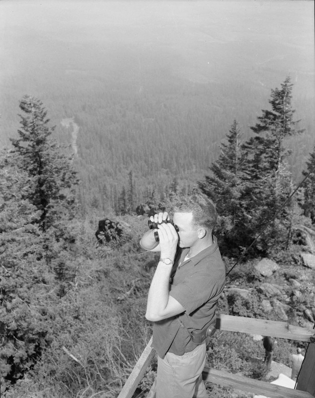 College of Forestry student at Moscow Mountain lookout, observing with binoculars.