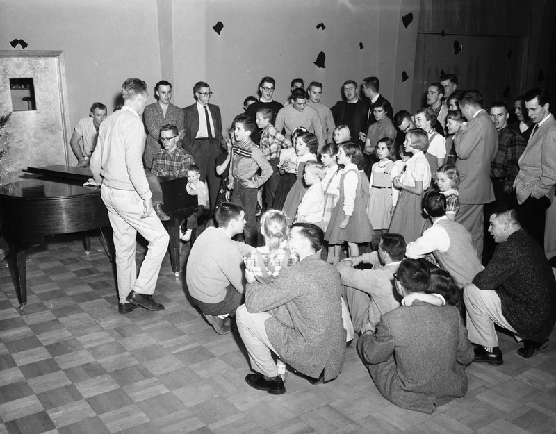 University of Idaho's Interfraternity Council (IFC) Christmas party for Moscow children. Children are shown sitting in a semicircle with the IFC members.