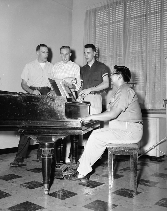Men singing around a piano at Lewis-Clark State College.