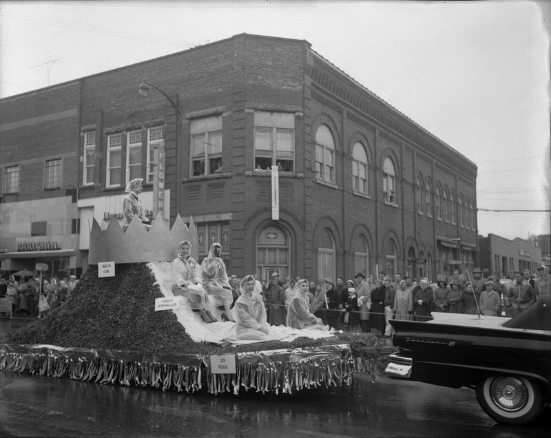 Homecoming Queen, Marilyn Crane, rides on a homecoming float with four other women, Shirley Hendriksson, Jan Novak, and two other unnamed women.