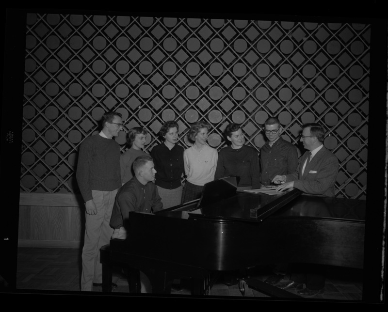 Glen Lockery, School of Music faculty, standing with members of the Vandaleers at a piano.