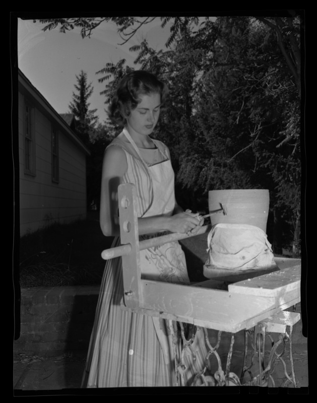 Mrs. James Douglass working with clay in Art and Architecture outside the Pottery Lab (later the Drama Annex) at University of Idaho.