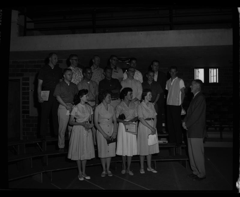 Group portrait of graduating seniors recieving special awards at the annual May Fete event in Memorial Gym. Individuals identified as listed. Front (l-r): Sandra Summerfield, unidentified, Nancy Wilmuth, Edna Mae Jones Neal. Second row (l-r): unidentified, Leo Tafolla, George Bertonneau, Ronald Goodwin, unidentified, Earl Owen. Back row (l-r): Jim Christensen, unidentified, Donald Hauxwell, Gerald Rohwein, Willian Orton, unidentified.