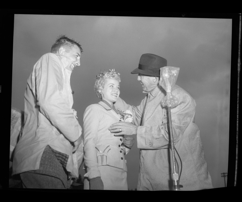 Homecoming queen Charmaine Deitz being crowned at the Homecoming Game by Dick Kerbs (left) and an unidentified man (right).