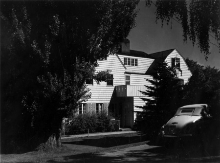 A photograph of Alpha Chi Omega sorority house with an automobile out front.