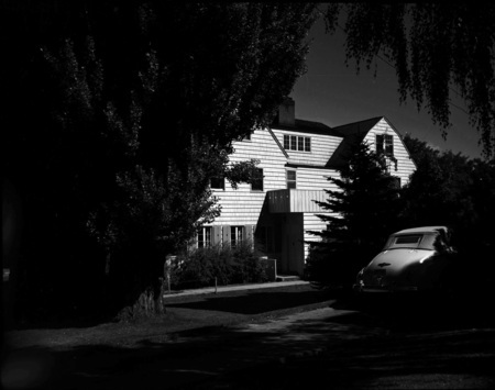 A photograph of Alpha Chi Omega sorority house with an automobile out front.