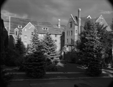 A photograph of Hays Hall, a five story brick and concrete building, built in 1926 as a women's dormitory. A woman can be seen walking in the foreground.