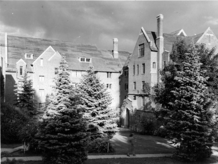 A photograph of Hays Hall, a five story brick and concrete building, built in 1926 as a women's dormitory. A woman can be seen walking in the foreground.