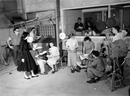 Students operating broadcasting equipment and reading scripts for television broadcasting class.