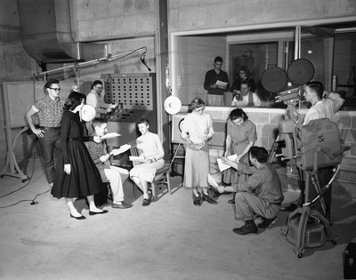 Students operating broadcasting equipment and reading scripts for television broadcasting class.