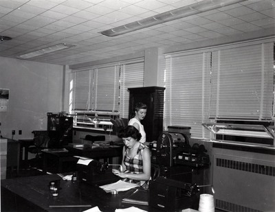 A photograph of the Argonaut office with one women at a typewriter and the other operating a newspaper printing press.
