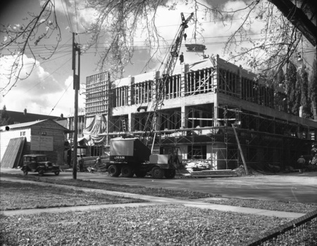 A photograph of the Student Union Building's 1950 addition under construction from across the street, showing a crane and automobile on the street.