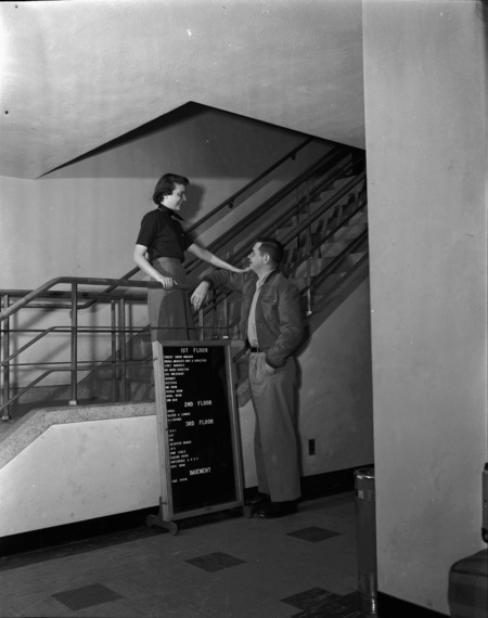 Two students socializing in the stairwell of the Student Union Building.