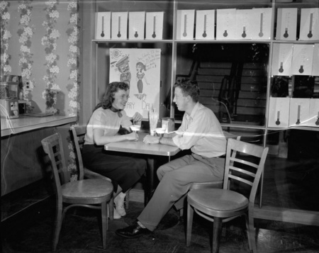 Richard Gibbs and an unidentified coed sit at a cafe table in the 1950 addition to the Student Union Building.