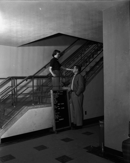 Two students socializing in the stairwell of the Student Union Building.