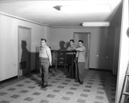 Three men moving a desk in the Student Union Building.