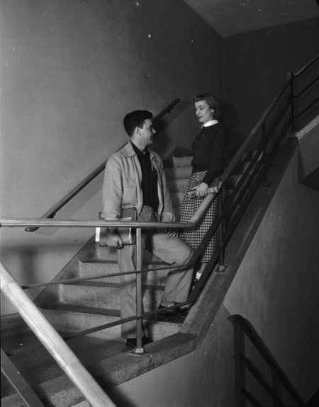 Two students socializing in the stairwell of the Student Union Building.