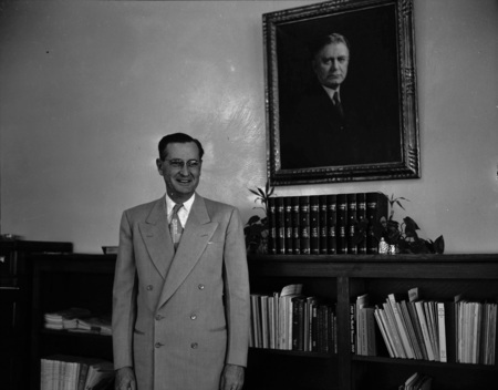 A portrait of President J.E. Buchanan standing in front of a bookshelf.