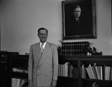 A portrait of President J.E. Buchanan standing in front of a bookshelf.