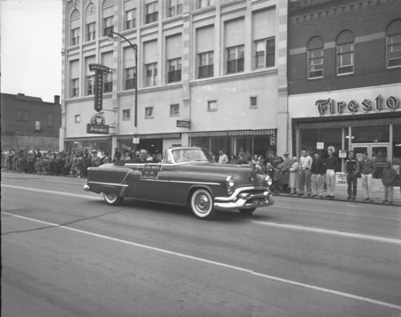 A photograph of Grand Marshal A.B. Guthrie Jr. and his wife driving in the Homecoming Parade.