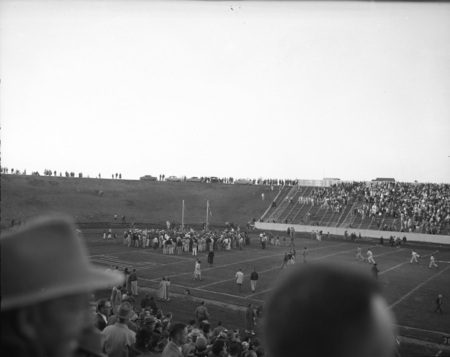 A crowd gathers on the football field at the Homecoming game.