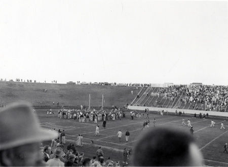A crowd gathers on the football field at the Homecoming game.