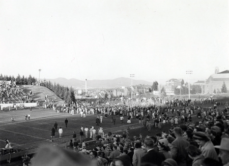 A crowd gathers on the football field at the Homecoming game.