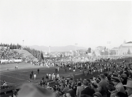 A crowd gathers on the football field at the Homecoming game.