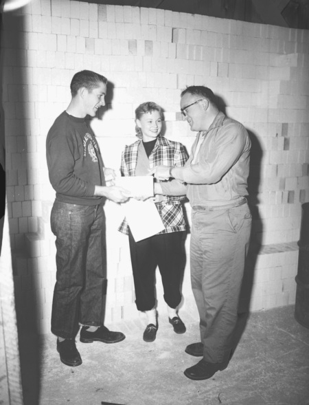 Geology Professor B. Rackham discussing documents with two students.