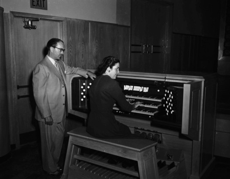 Hall Macklin watching colleague Marian Frykman play the organ.