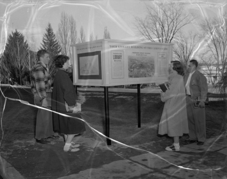 Students read a sign on the building of the University of Idaho library.