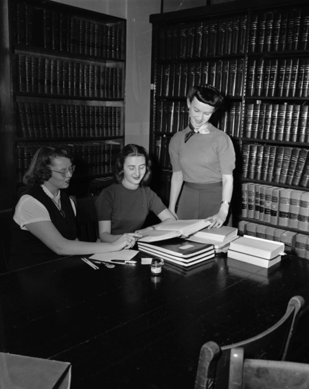 Argonaut staff reading out of a book in a library.