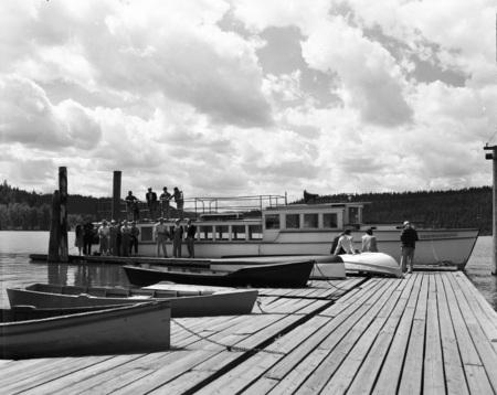 Students stand on a dock by a boat.