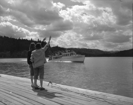 People wave at a boatful of students from the docks.