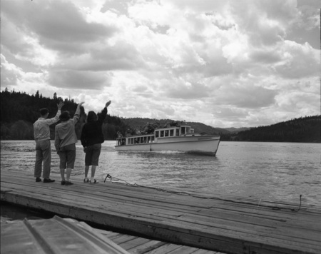 People wave at a boatful of students from the docks.