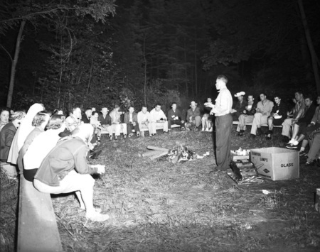 Students sit around a campfire.