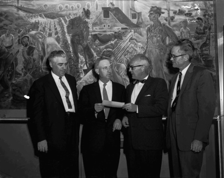 Left to right: J.W. Kipper, Dean James Kraus, Joe McArthur, and Associate Dean Don Marshall receiving a check in front of the Kirkwood mural in the Agricultural Science Building.