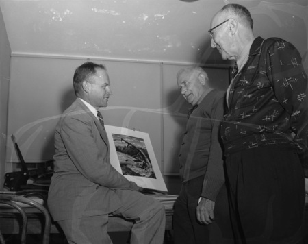 Roy Bell accepts L&C camera club pictures for display from Ira Dole and George Barkhoff.