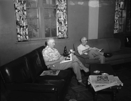 Two unidentified men reading the paper from the Public Utilities Conference.