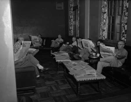 Group photograph of men reading the paper from the Public Utilities Conference.